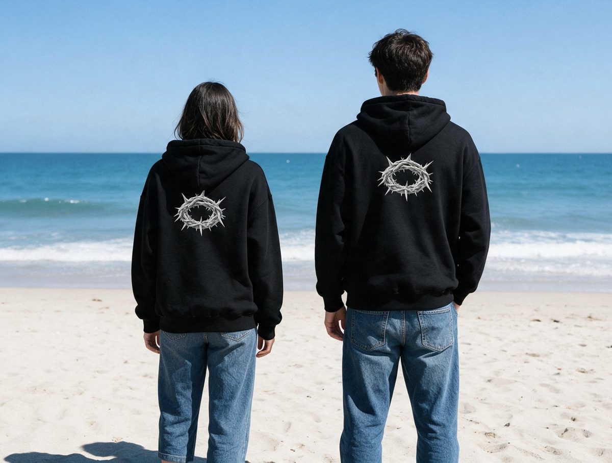 Couple wearing the Redeemed zip hoodie on the beach, crown of thorns back